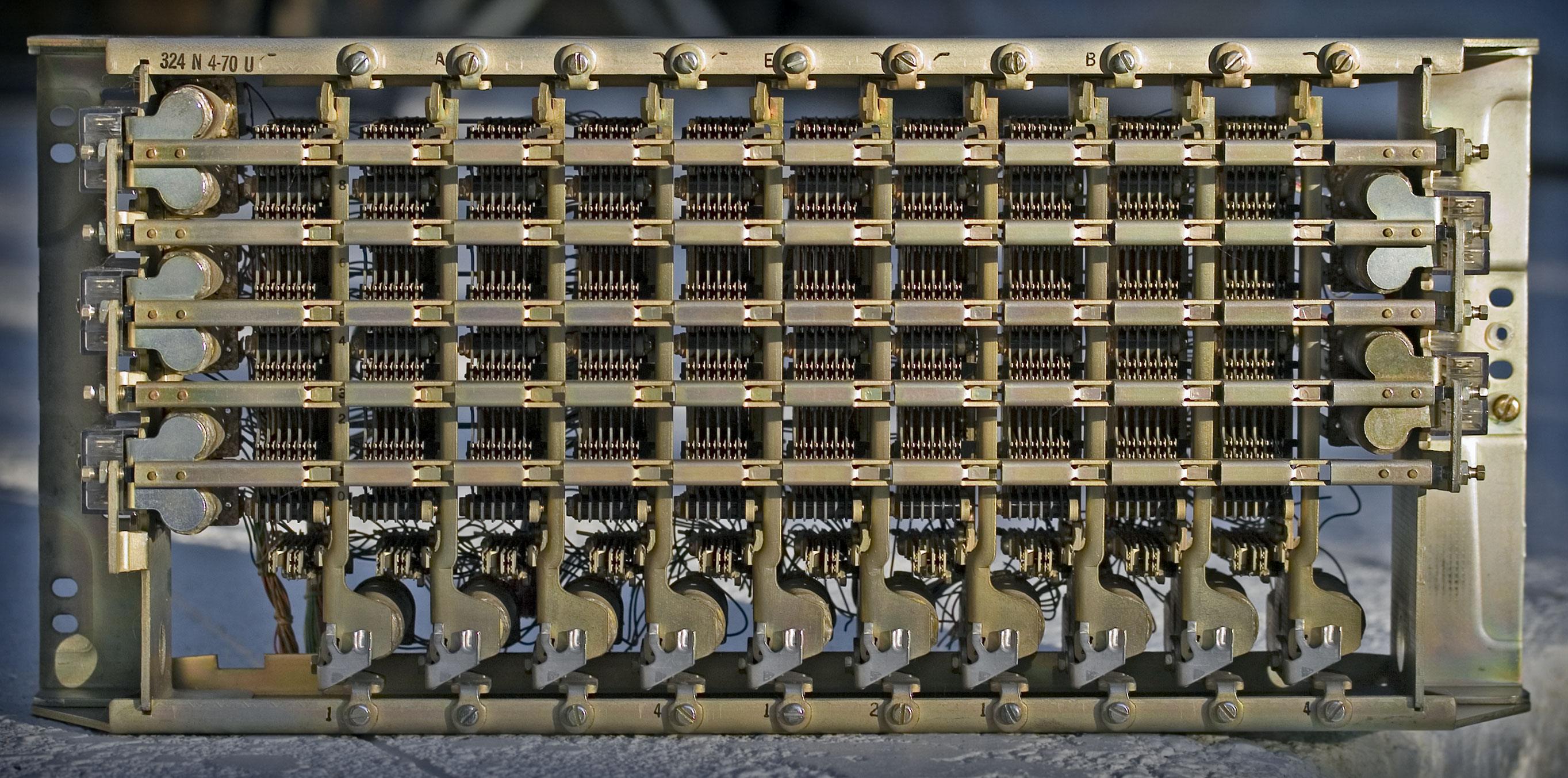 Figure 1 — A crossbar switch: five horizontal selecting bars across the front, ten vertical holding bars, and the hold magnets along the bottom. Each selecting bar serves the row of contacts above it and the …